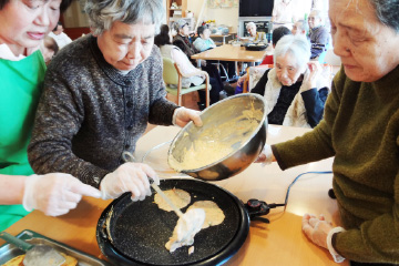 ホットプレートでホットケーキを一緒に作るお客様とスタッフの画像